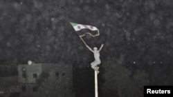 Syria -- A demostrator holds an opposition flag during a protest against regime at Kfr Suseh area in Damascus, 02Jul2012