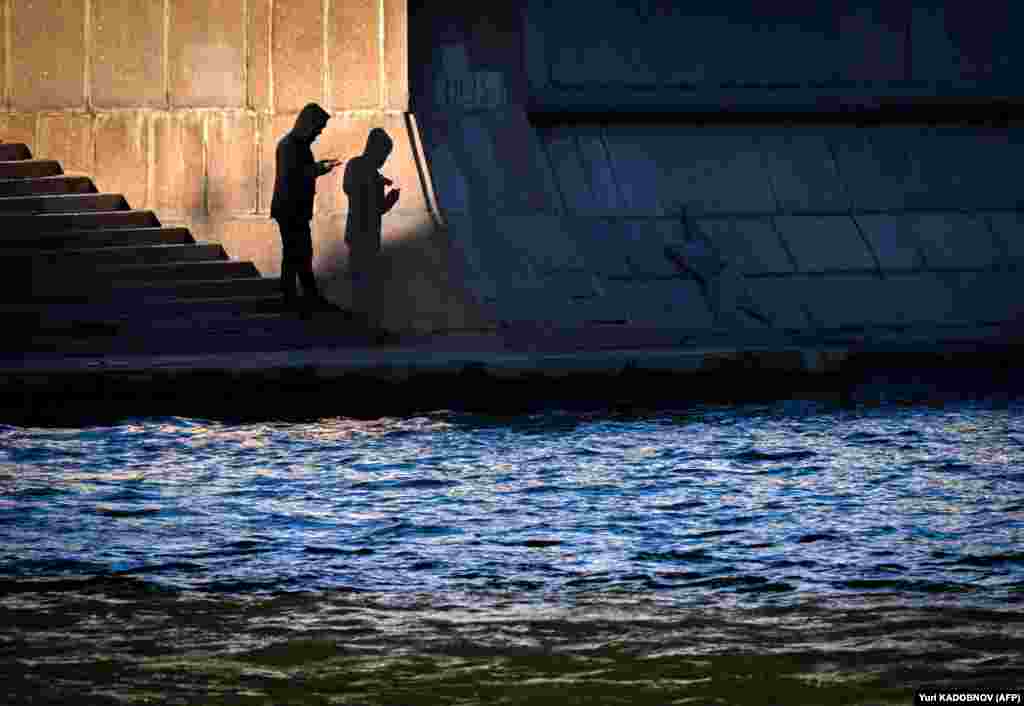 A man looks at his mobile phone on the banks of the Moskva River embankment in central Moscow.&nbsp;