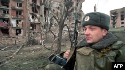 Российский солдат на фоне разрушенных зданий в Грозном. 29 января 2000 года