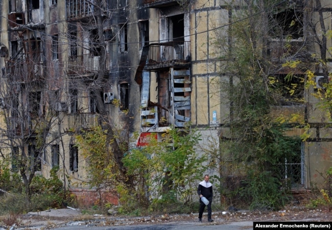 Мужчина проходит мимо поврежденного российскими обстрелами дома, во временно оккупированном Мариуполе. Украина, 9 ноября 2022г