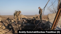 Українські військові оглядають підбитий танк у Снігурівці