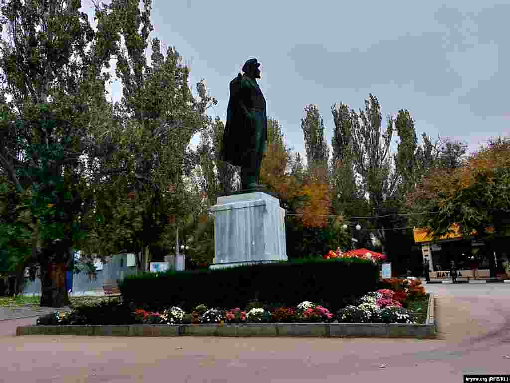 Разноцветная листва на деревьях и цветы на клумбе возле памятника Ленину в Феодосии &ndash; последние краски уходящей осени в Крыму