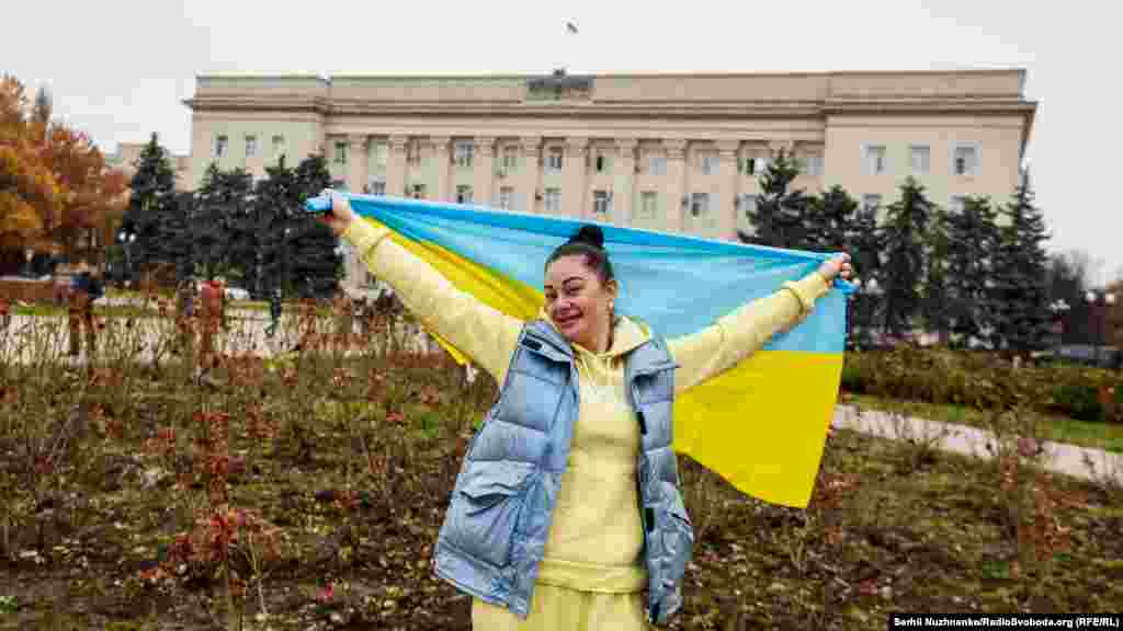 Местная жительница с национальным флагом Украины перед зданием ОГА в Херсоне, 13 ноября 2022 года
