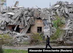 Мужчина проходит мимо разрушенного российскими обстрелами дома, во временно оккупированном РФ Мариуполе. Украина, 9 ноября 2022 года