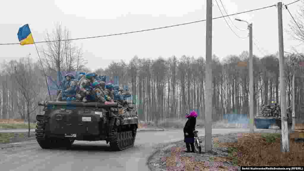 Сльози вдячності. Жінка вітає воїнів ЗСУ, які під державними прапорами рухаються звільненим від окупантів населеним пунктом.&nbsp;&nbsp;