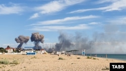 За пляжем у поселка Новофедоровка видны черные клубы дыма от взрывов, которые произошли на территории российского военного аэродрома, расположенного поблизости. Крым, Сакский район, 9 августа 2022 года