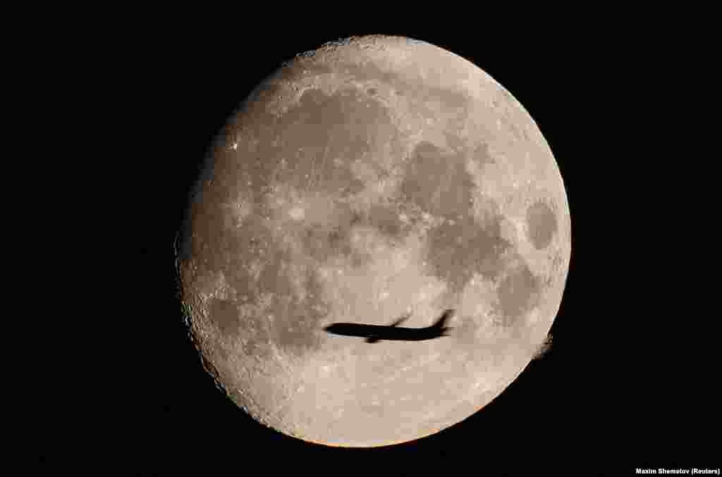A passenger plane is silhouetted against the moon in a photo taken in Moscow on August 9.