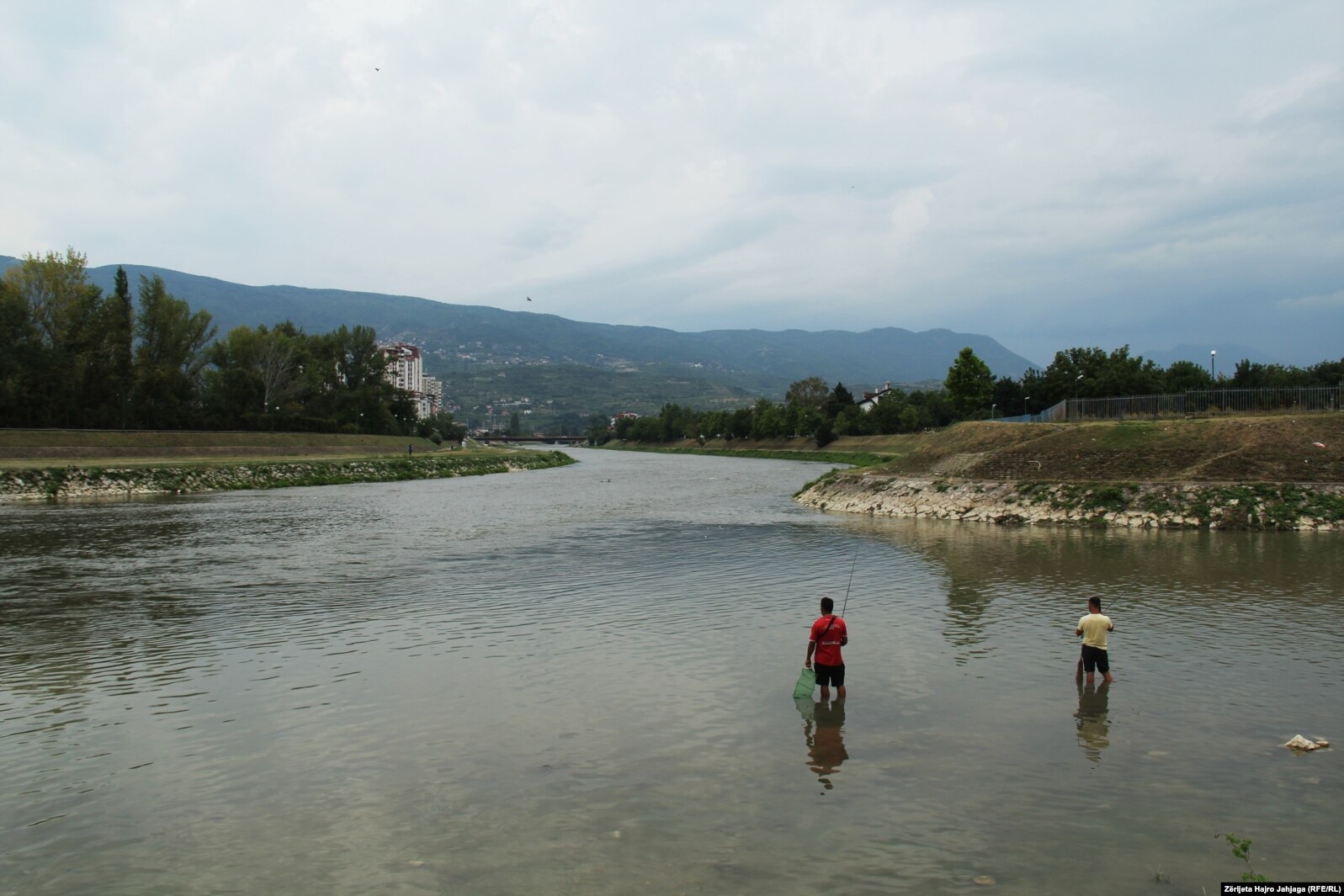 Disa qytetar duke peshkuar në Lumin Vardar në Shkup.