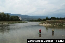 Disa qytetar duke peshkuar në Lumin Vardar në Shkup.