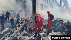 Armenia - Rescue workers sift through the rubble searching for possible survivors and recovering bodies at the site of a Yerevan shopping center where a fireworks warehouse exploded on August 14, triggering a massive fire.