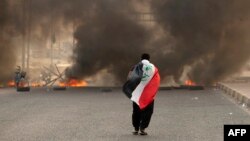 یک هوادار مقتدی صدر در میان دود ناشی از آتش زدن لاستیک‌ها در بغداد