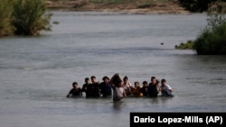 Migránsok kelnek át a Rio Grande folyón Mexikóból az Egyesült Államokba a texasi Eagle Passnál 2022. május 20-án