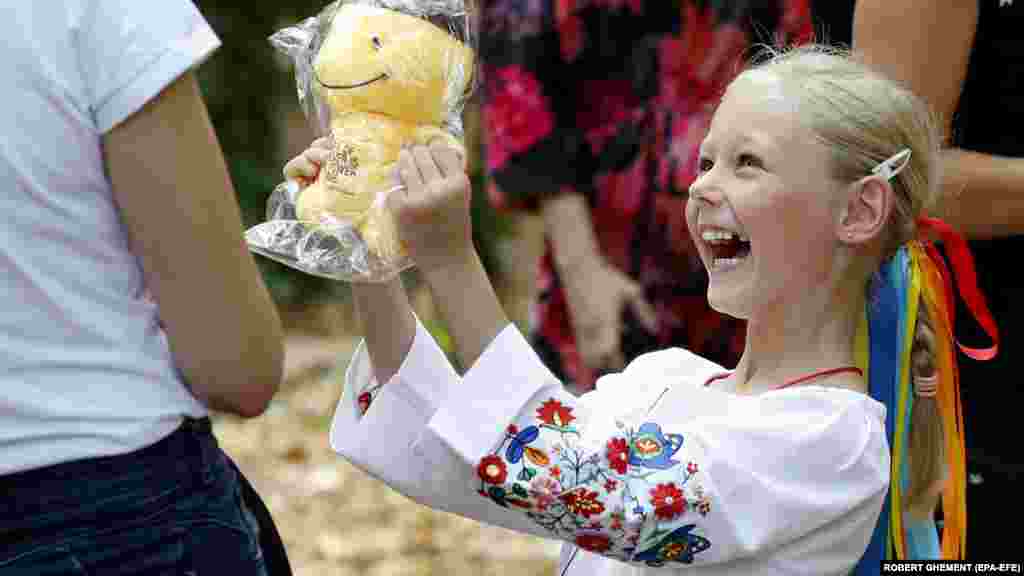 O fetiță din Ucraina primește un ursuleț de pluș la un eveniment pentru copiii refugiați care a avut loc la București pe 24 august. Ucraina a marcat în acea zi 31 de ani de la declararea independenței de URSS. (EPA-EFE/Robert Ghement)