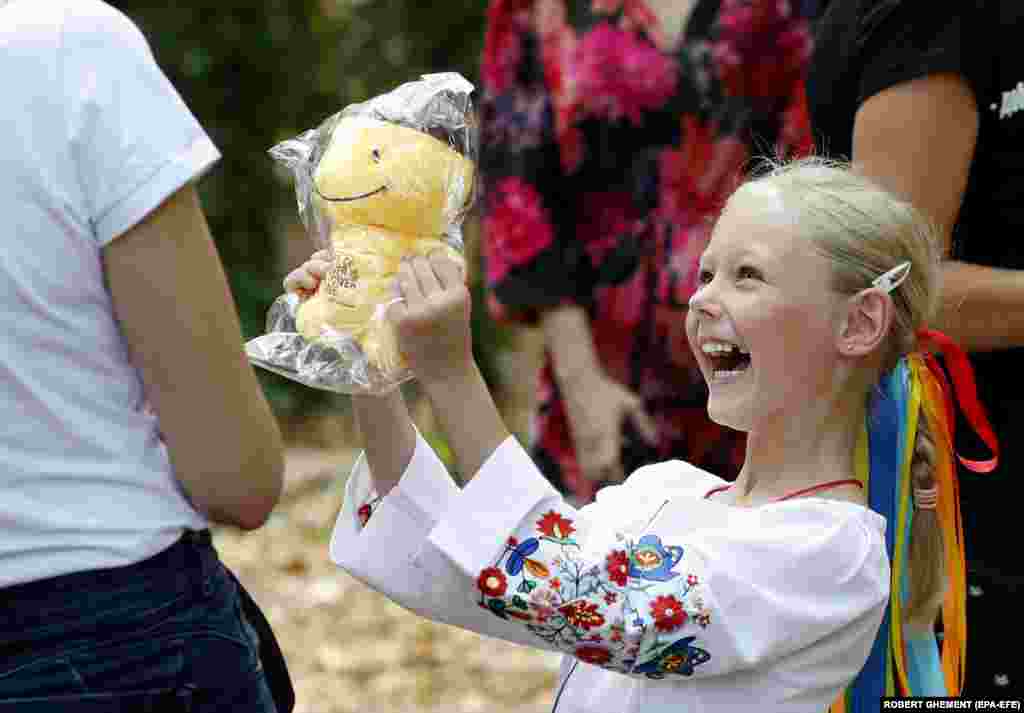 A young Ukrainian girl shows her mother her new toy during an event dedicated to Ukrainian refugee children in Bucharest.