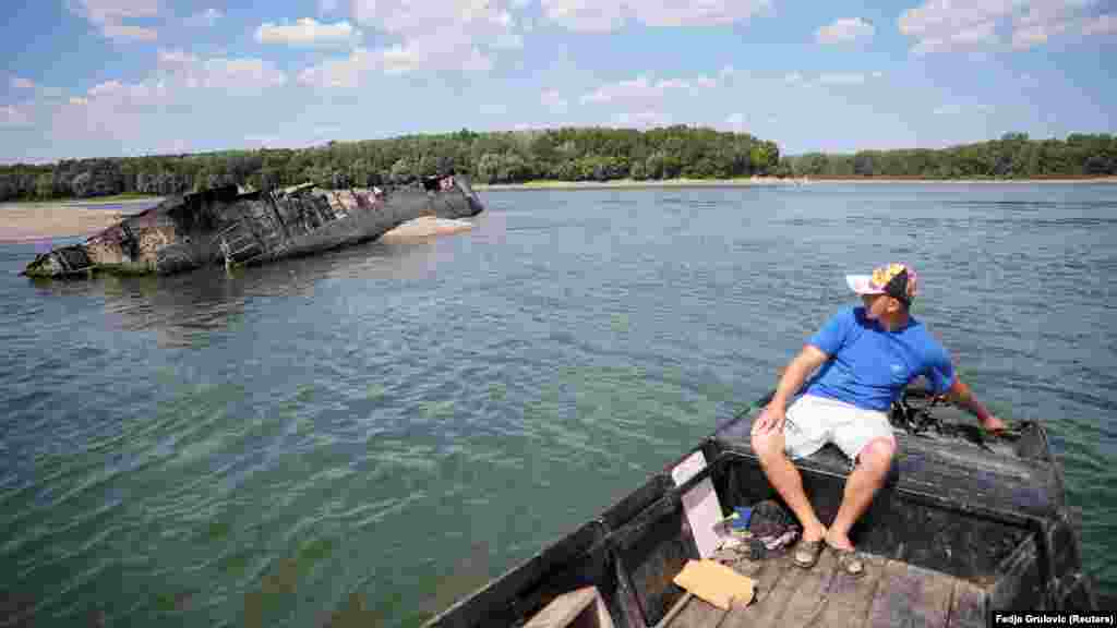 Ivica Škodrić, lokalni ribar u Prahovu, upravlja svojim čamcem blizu jednog od brodova. Neki od ovih brodova još uvijek imaju kupole, komandne mostove, razbijene jarbole i savijene trupove, dok su drugi uglavnom potopljeni ispod pješčanih sprudova.