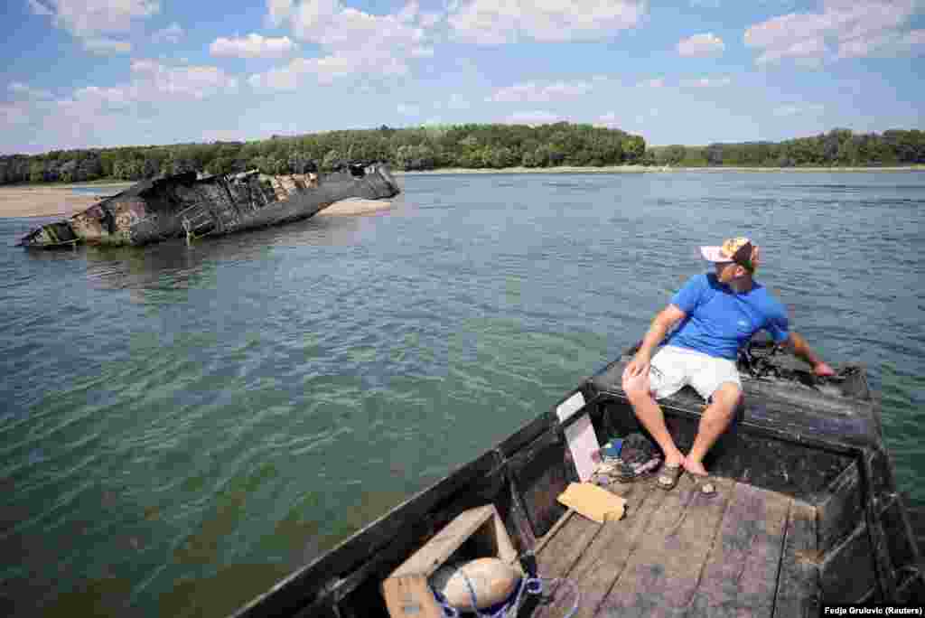 Ivica Skodric, a local fisherman in Prahovo, steers his boat close to one of the ships. Some of these vessels still have turrets, command bridges, shattered masts, and bent hulls, while others are mostly submerged beneath sandbanks.