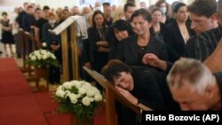 People react next to photographs of the dead during a commemoration ceremony in honor of the victims in Cetinje on August 14.