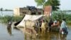 People stand outside their flooded house following rains and floods during the monsoon season in Sohbatpur, Pakistan, on August 28.