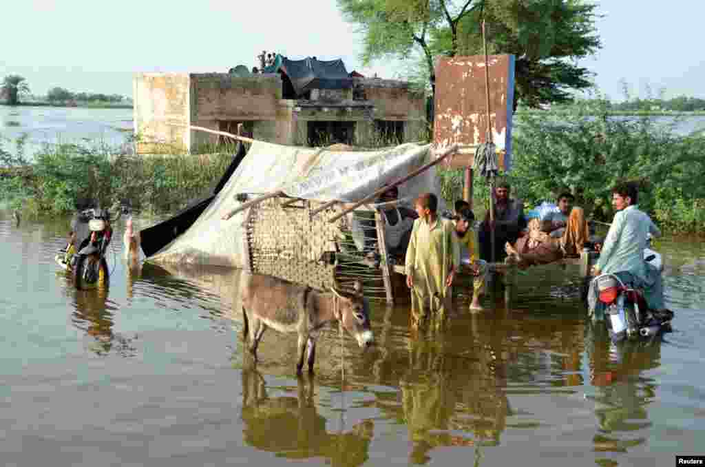 Një familje para shtëpisë së saj të përmbytur, pas shiut dhe vërshimeve në qytetin e Sohbatpur, 28 gusht.