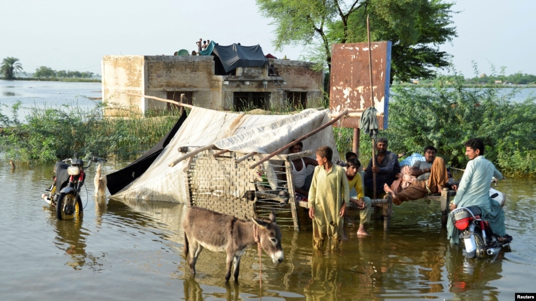 People stand outside their flooded house following rains and floods during the monsoon season in Sohbatpur, Pakistan, on August 28.