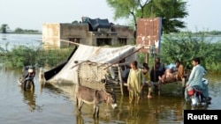 People stand outside their flooded house following rains and floods during the monsoon season in Sohbatpur, Pakistan, on August 28.
