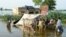 People stand outside their flooded house following rains and floods during the monsoon season in Sohbatpur, Pakistan, on August 28.