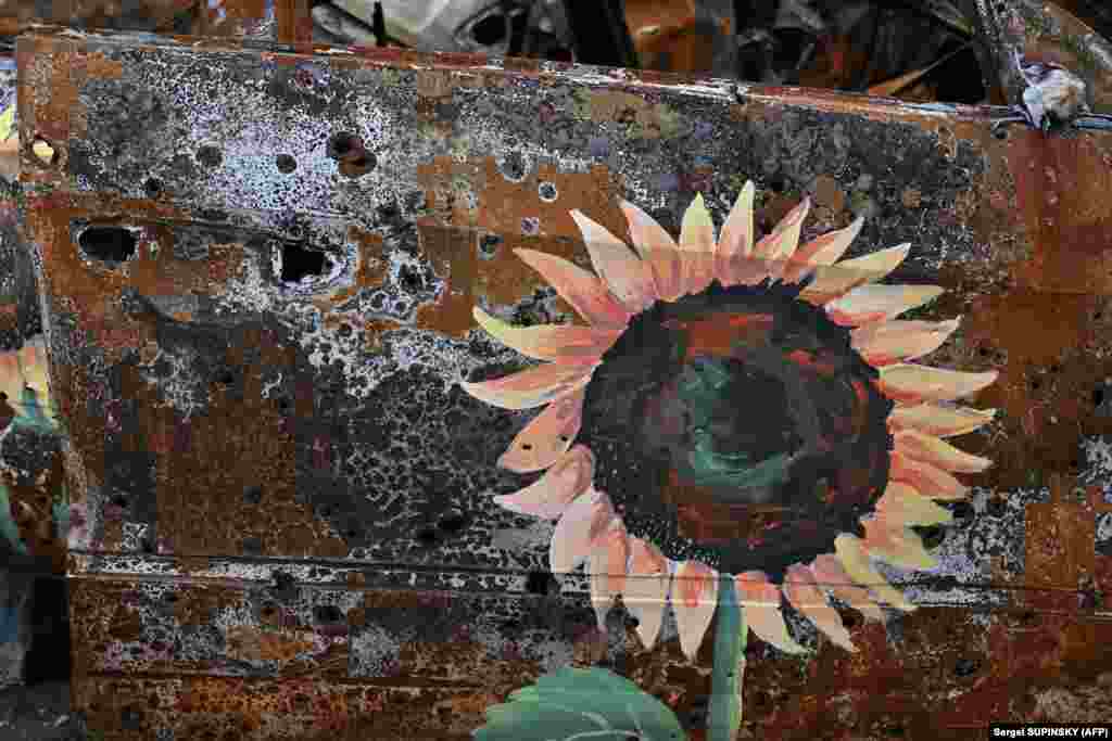 A sunflower, the national flower of Ukraine, is seen on a burned-out car in Irpin, near Kyiv. The installation is causing dismay among some Ukrainians, while others hail the novel approach to raising money for the nation&#39;s artistic community, which is languishing during the war.