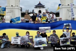 Slavic people living in Taiwan display posters and a Ukrainian flag during a rally in front of the Chiang Kai-shek Memorial Hall in Taipei on May 8, 2022.