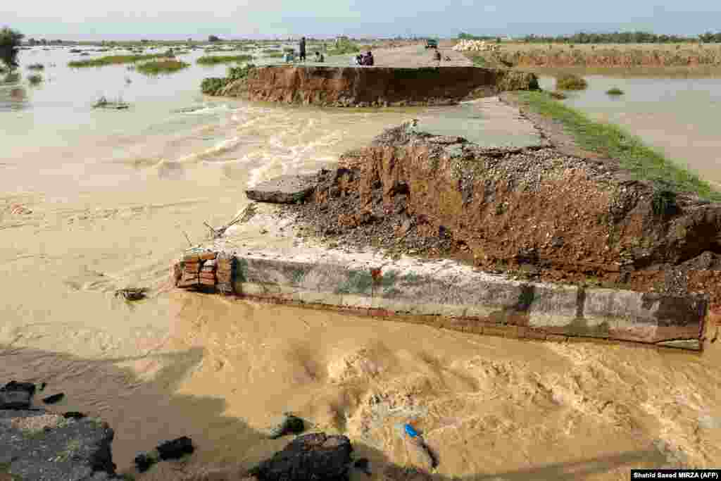 People sit on a damaged road after heavy monsoon rainfall in Rajanpur district of Punjab Province, Pakistan. Figures from the national disaster agency showed on August 25 that 903 people had died in the floods since June, and over 180,000 were forced to flee their rural homes.