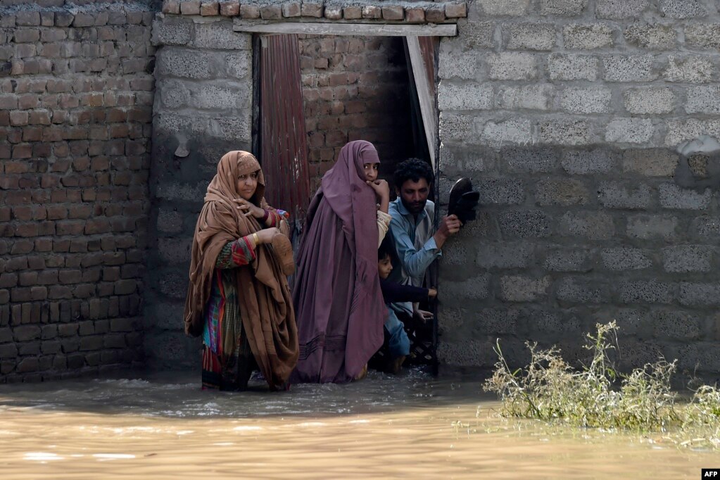 Një familje duke pritur për t'u evakuuar para një shtëpie të përmbytur në rrethin Charsada të provincës Khyber Pakhtunkhva, 29 gusht. Ekipet e shpëtimit po bëjnë përpjekje për të arritur në fshatrat e izoluara në rajonet malore në veri të vendit. &nbsp;