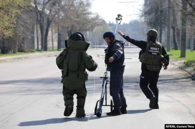 Sappers check for mines along a street in Kharkiv.
