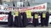 Fotografie de arhivă realizată la 17 februarie 1989: femei iraniene sunt văzute ținând bannere pe care scrie "Holly Koran" și "Kill Salman Rushdie" în timpul unei demonstrații împotriva scriitorului britanic Salman Rushdie la Teheran.