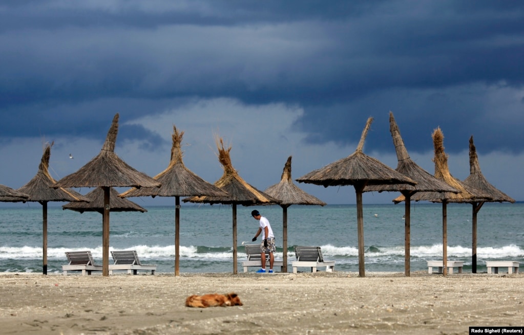 Një burrë lyen një shtrat plazhi pa vizitorë në Navodari, Rumani.