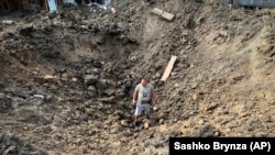 Мешканець стоїть у вирві після обстрілу РФ в Дергачах, на околиці Харкова, 26 серпня 2022 року. Фото ілюстративне.