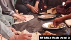 Egy afganisztáni család ebéd közben. A családfő azt mondja, vacsorát már nem tud biztosítani a gyerekeknek. Tarinkot, 2022. augusztus 10.