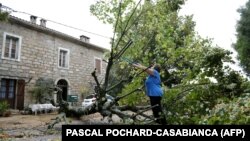 Žena u Maratu, Korzika, uklanja grane sa stabla srušenog u oluji, 18. avgust 2022.