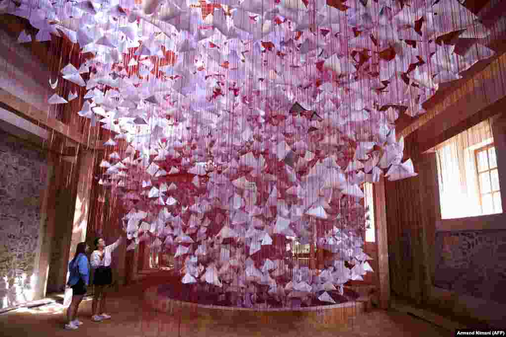 Visitors look at an installation called Tell Me Your Story by Japanese artist Chiharu Shiota in Pristina on August 16. Manifesta 14 is driven by what organizers say is &quot;Pristina&#39;s call and the global need to reclaim and reimagine public spaces.&quot; &nbsp;