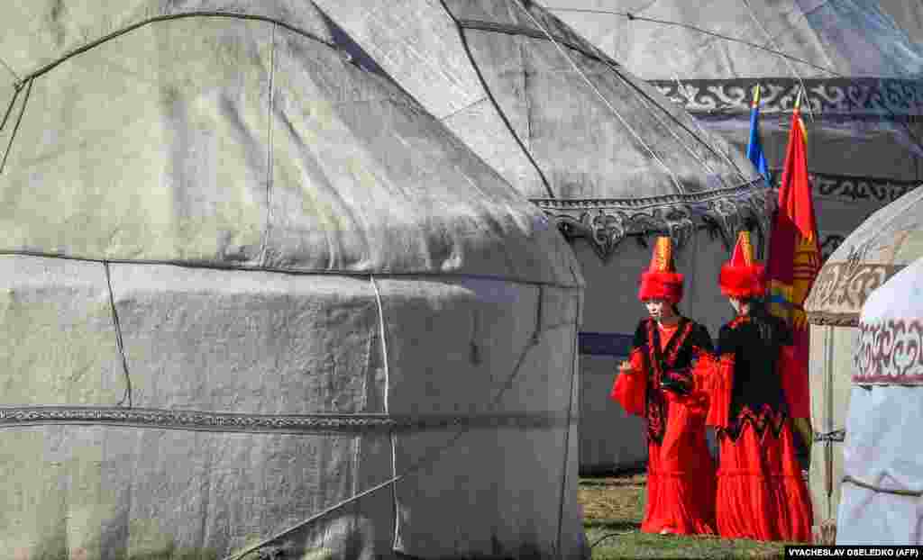 Kyrgyz women wearing traditional clothes walk past portable yurts during a hunting festival in the Chunkurchak Gorge, some 30 kilometers outside Bishkek.