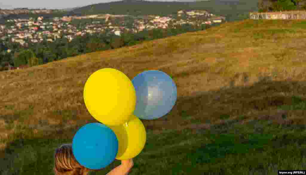 Жители Симферополя запускают воздушные шарики в цветах украинского флага на Петровских скалах, 23 августа 2022 г.