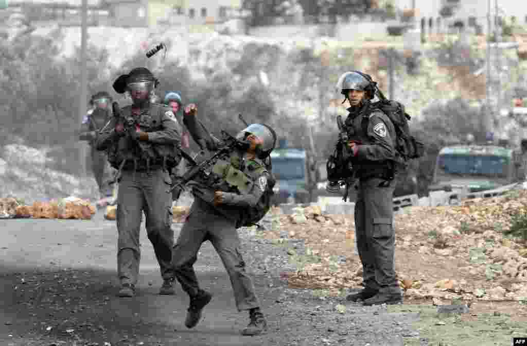 An Israeli soldier throws a smoke grenade at Palestinian protesters during a demonstration against the expropriation of Palestinian land by Israel in the village of Kfar Qaddum. (AFP/Jaafar Ashtiyeh)