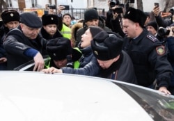 Полицейские насильно сажают в автомобиль журналистку Ингу Иманбай. Алматы, 22 февраля 2020 года.