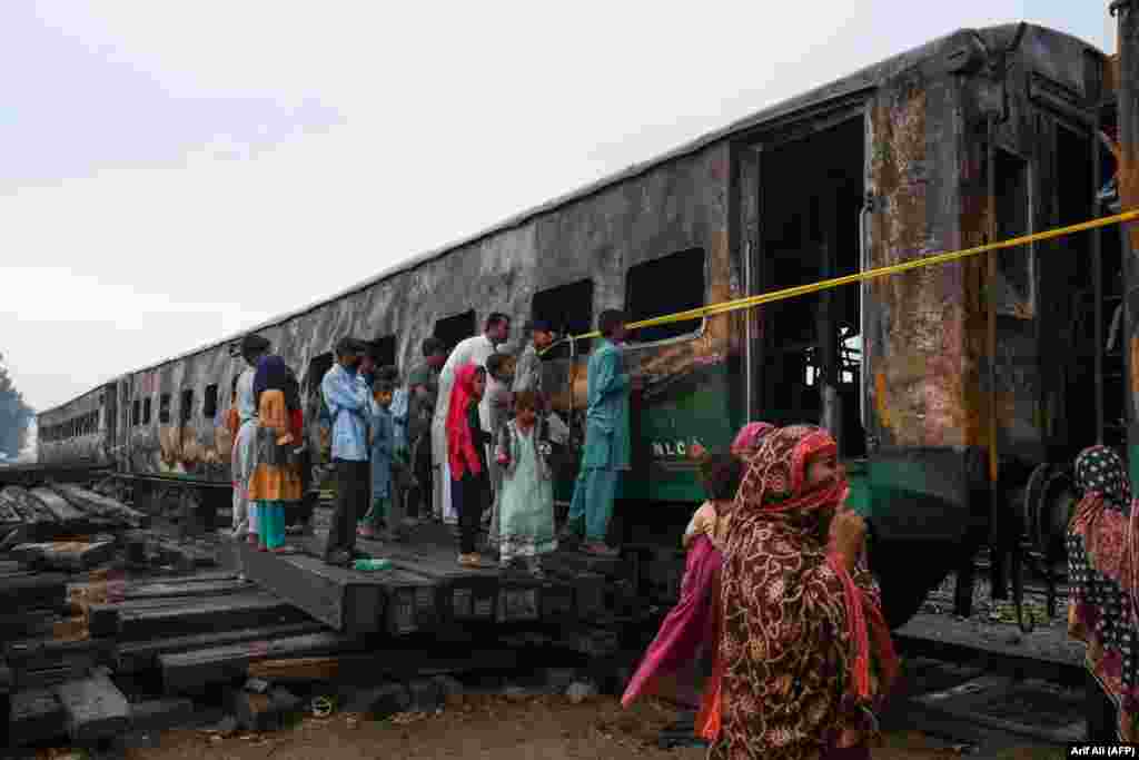 People look at burnt-out carriages a day after a passenger train caught fire in Rahim Yar Khan, Pakistan, killing dozens of people. (AFP/Arif Ali)