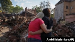 Ukrainian women hug in front of a building destroyed during a Russian missile strike in Kharkiv on August 18.