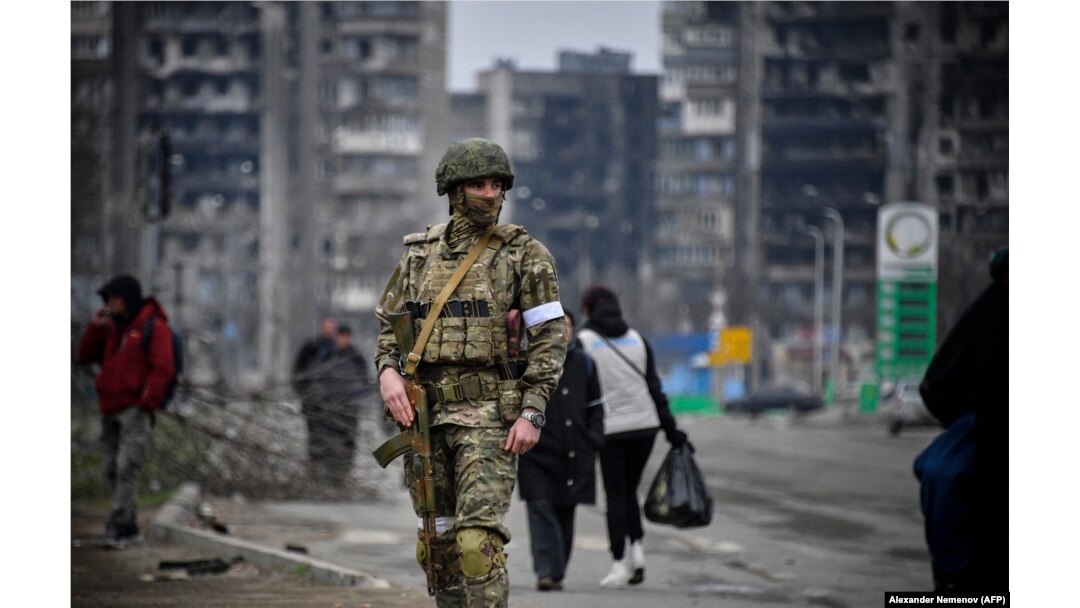 A Russian soldier patrols a street in the devastated Ukrainian city of Mariupol in April.