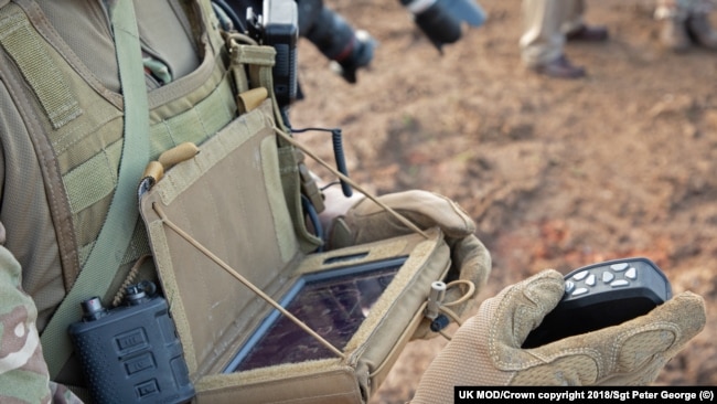 Британски войник, който гледа дисплея, докато управлява дрон