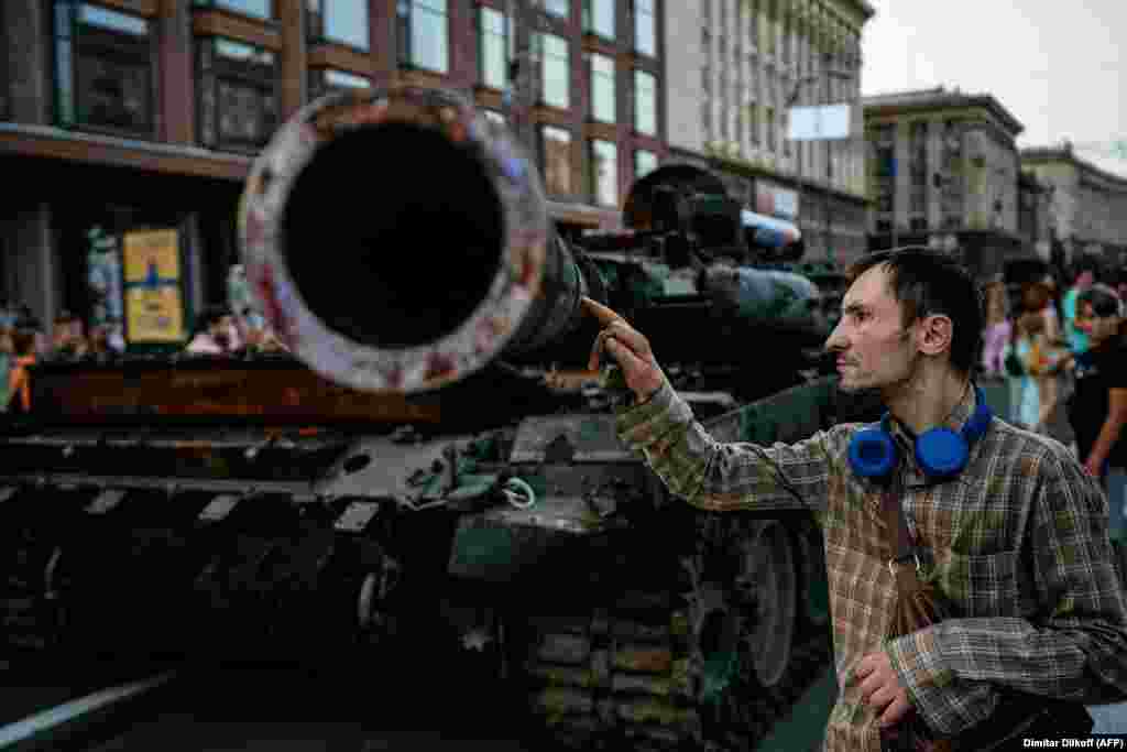 Egy férfi megérint egy harcképtelenné tett orosz tankot