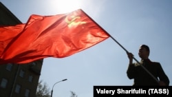 Мужчина держит флаг СССР, символизирующий коммунизм.