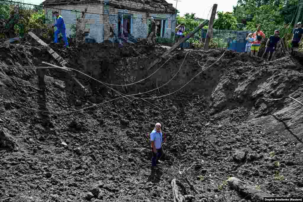 Egy férfi áll egy kráterben, amelyet egy orosz rakétacsapás hagyott maga után Kusuhum településen, az ukrajnai zaporizzsjai területen 2022. augusztus 10-én