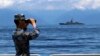 Китайский военный наблюдает за перемещением тайваньского фрегата