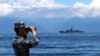 Kínai katona figyel távcsővel egy tajvani fregattot a legutóbbi hadgyakorlaton, 2022. augusztus 5-én